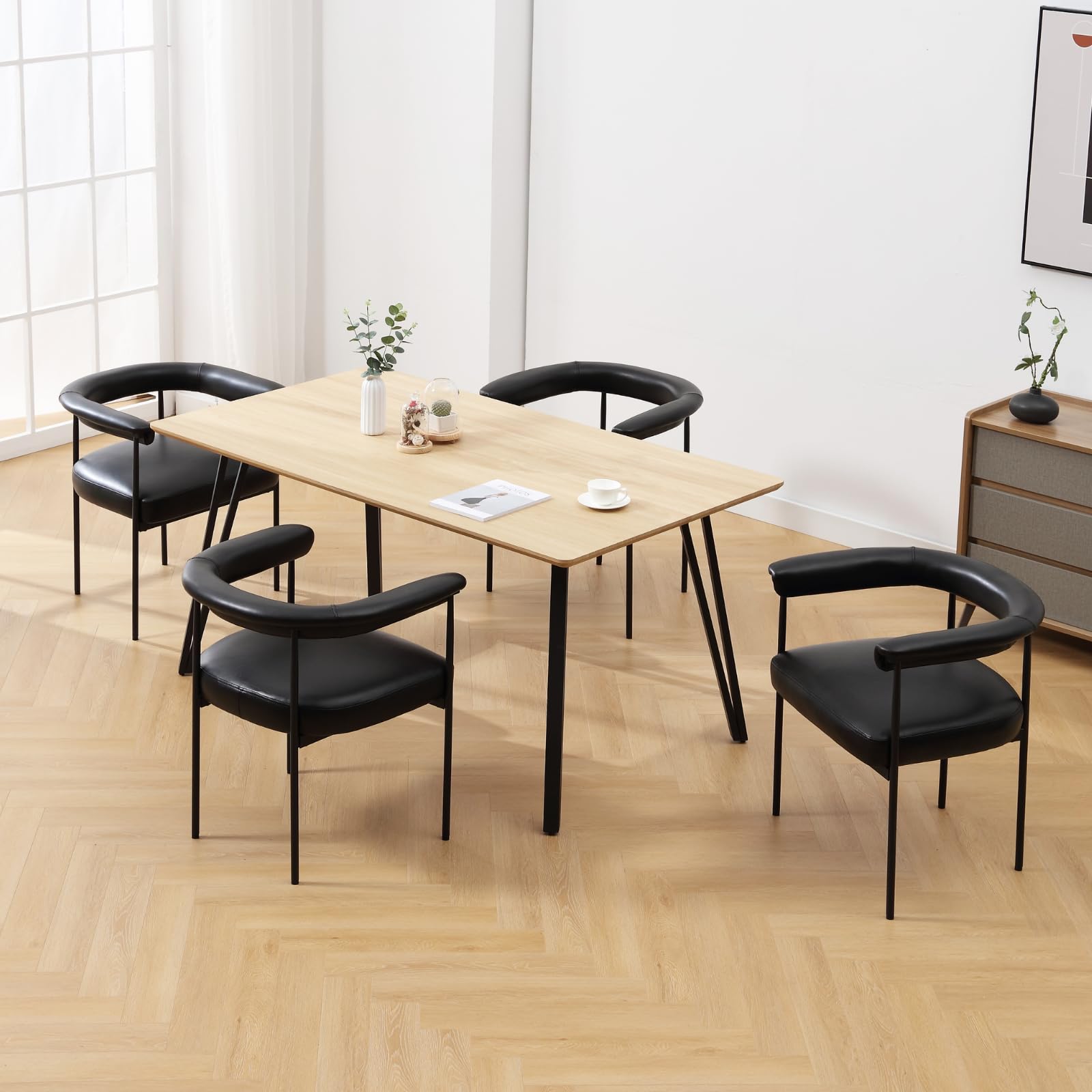 Set of two black barrel dining chairs around a table in a bright room