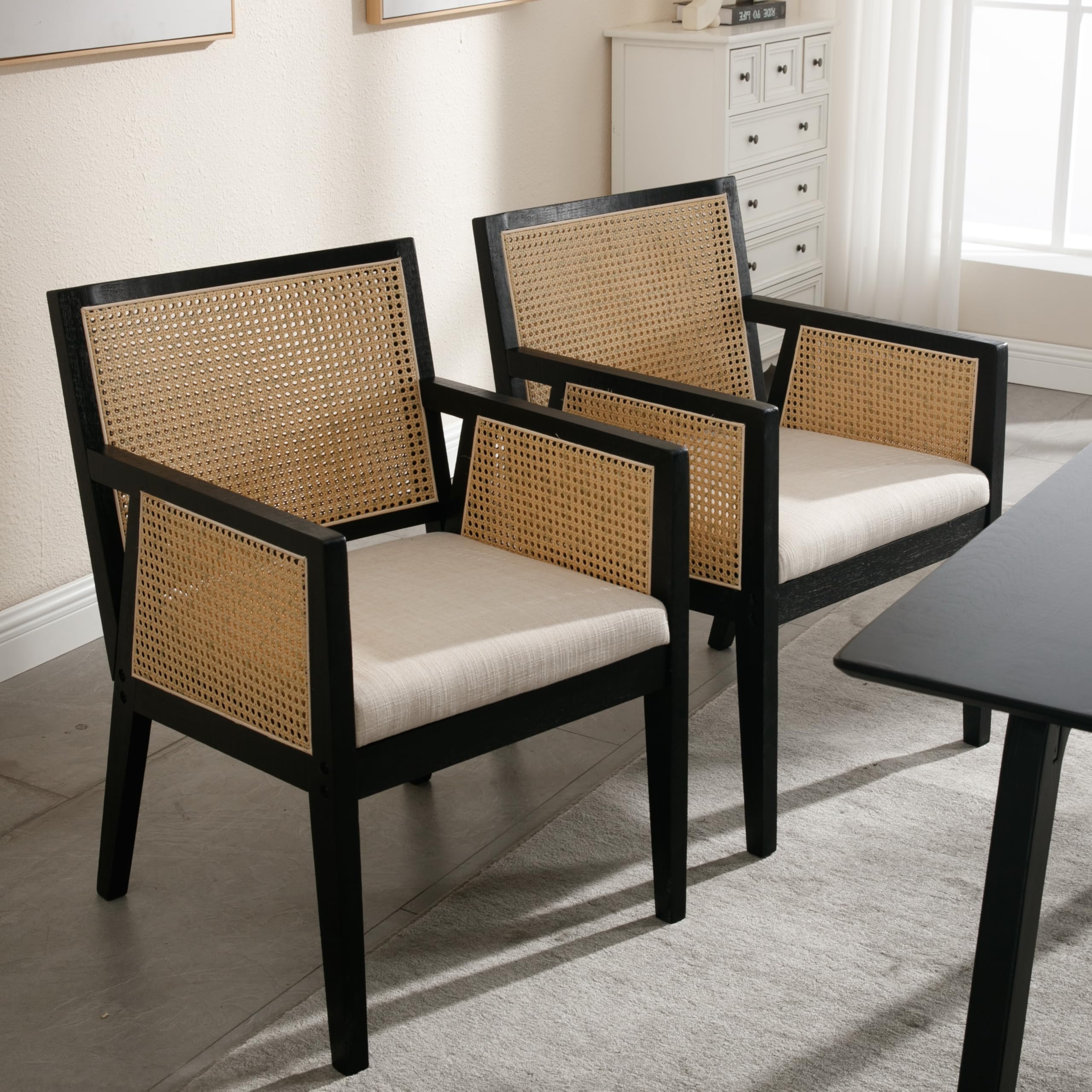 Three black dining chairs with rattan backs around a table