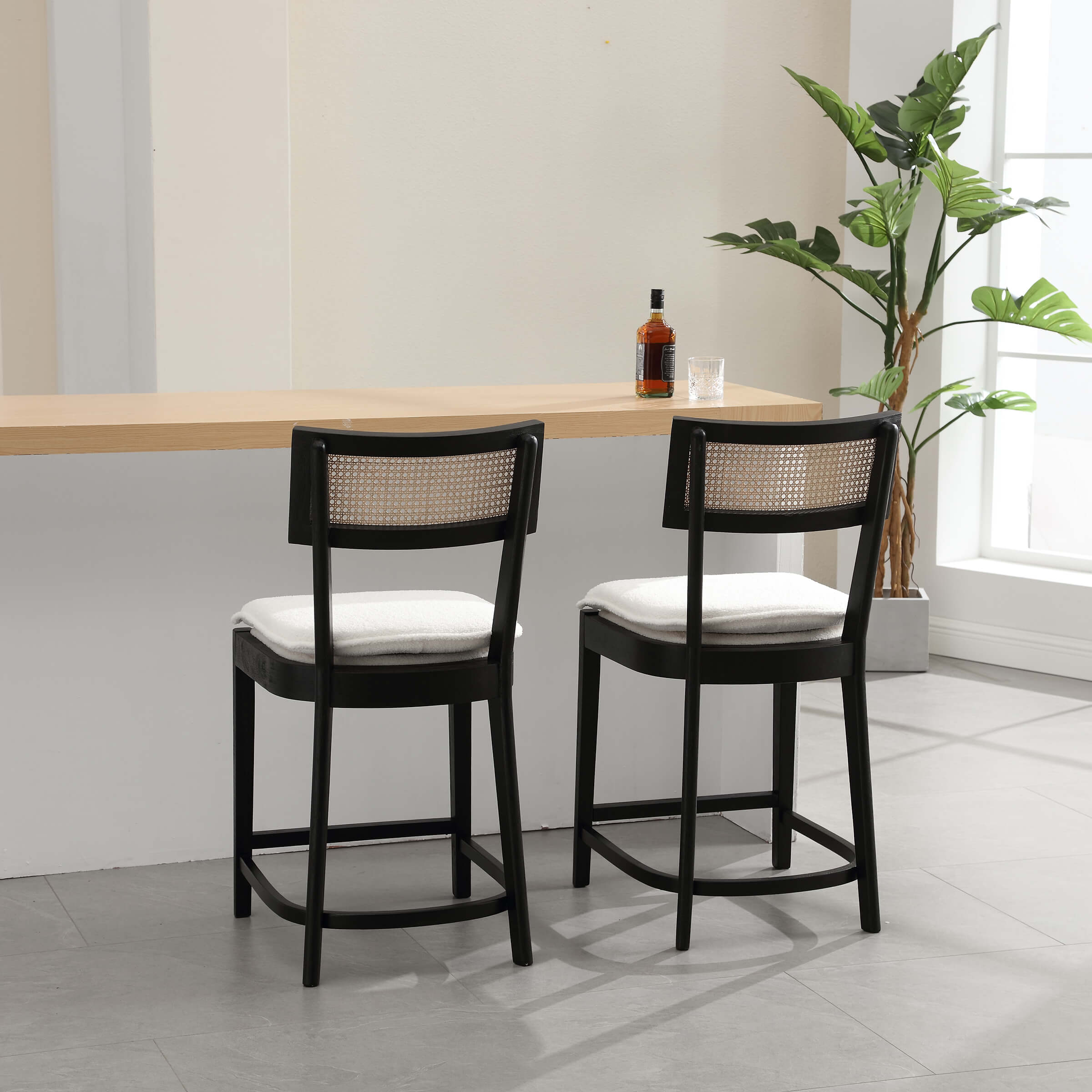 Two stools at a counter with bottle and glass