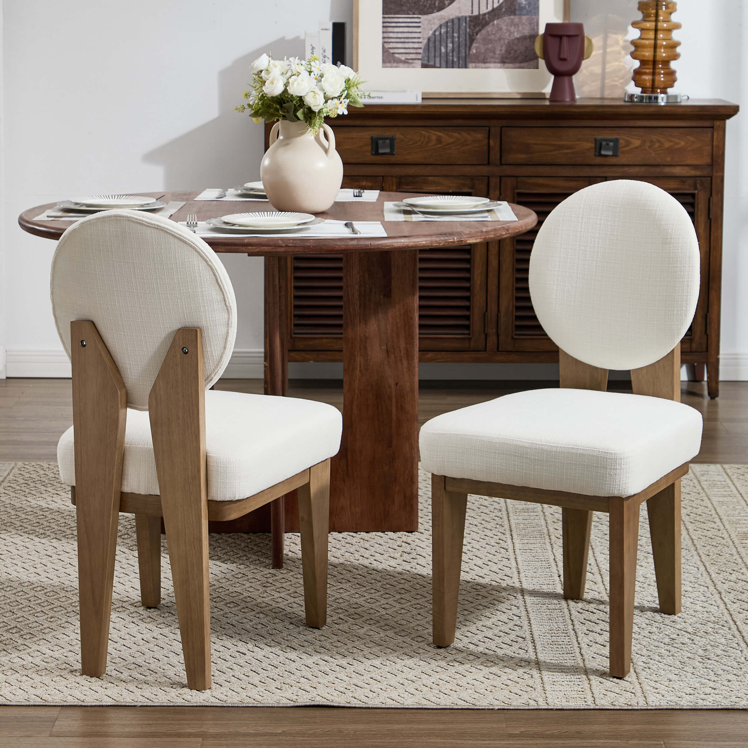 Set of four cream upholstered chairs around a round wooden table