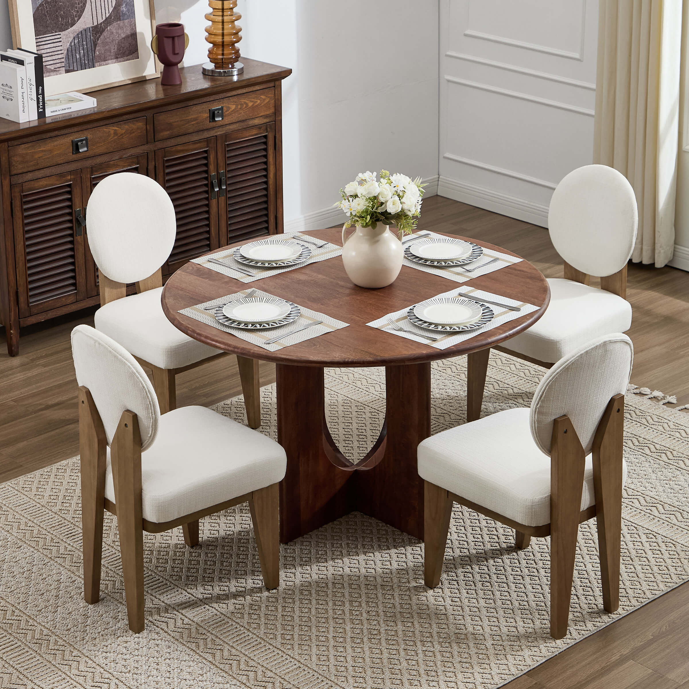 Round dining table with four cream chairs around it