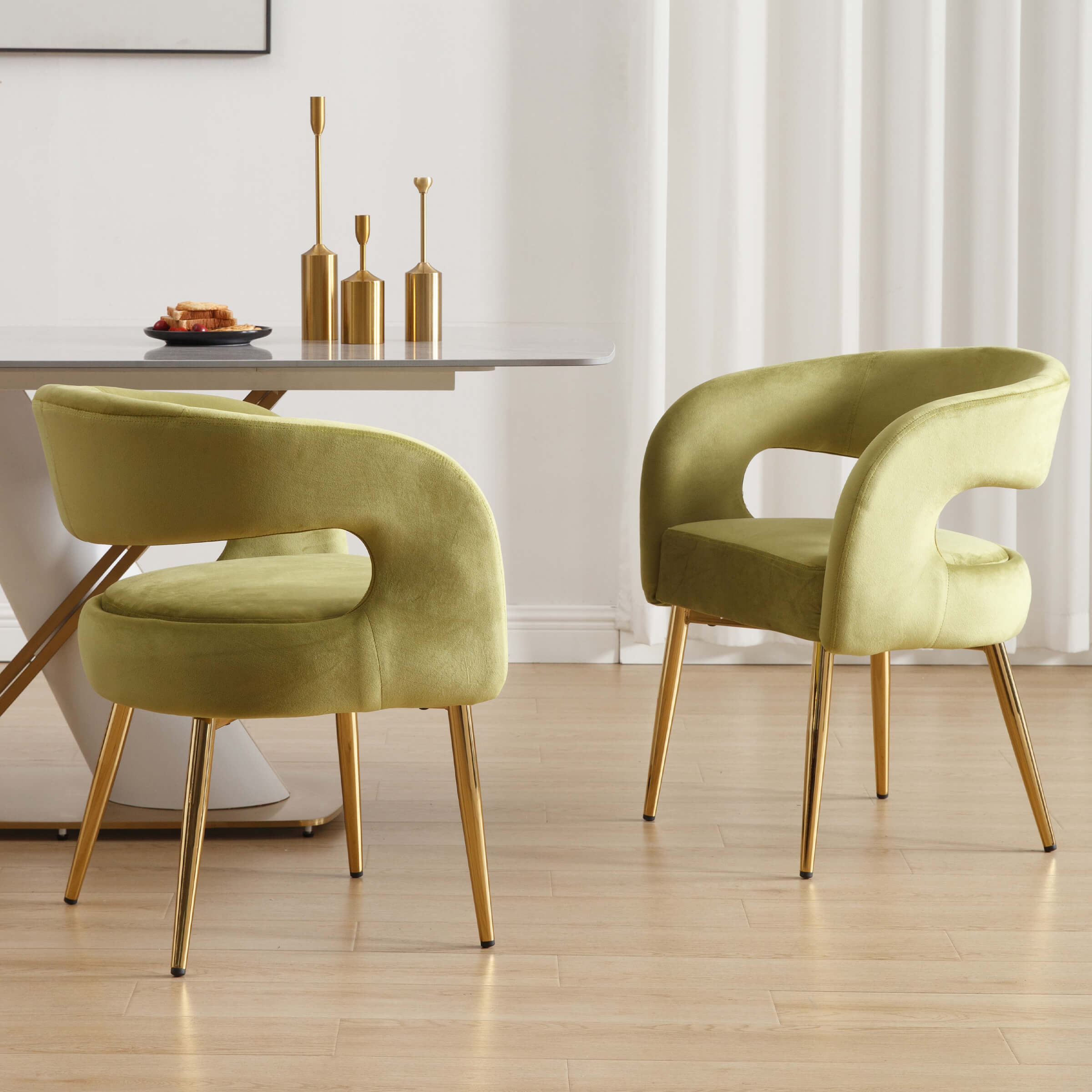 Two green velvet chairs around a dining table