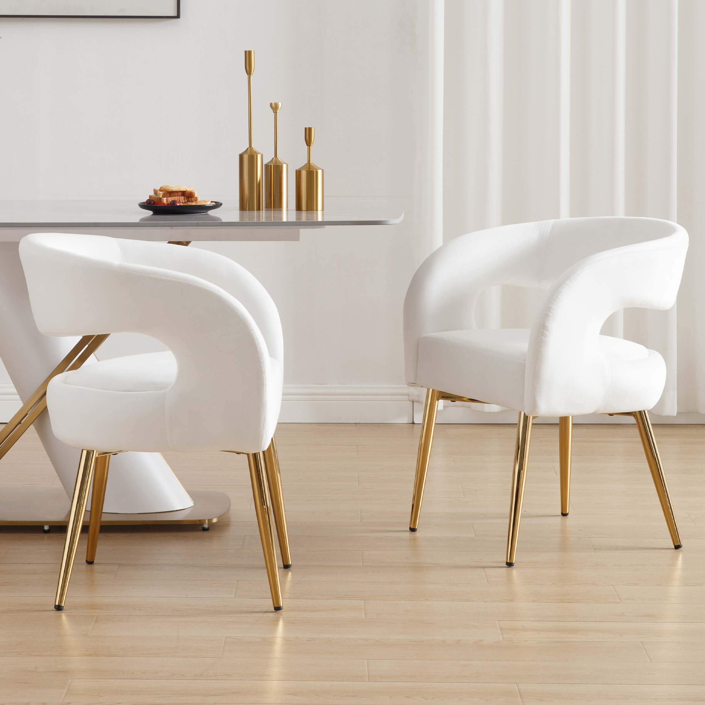 Front and side views of white velvet dining chairs around a table