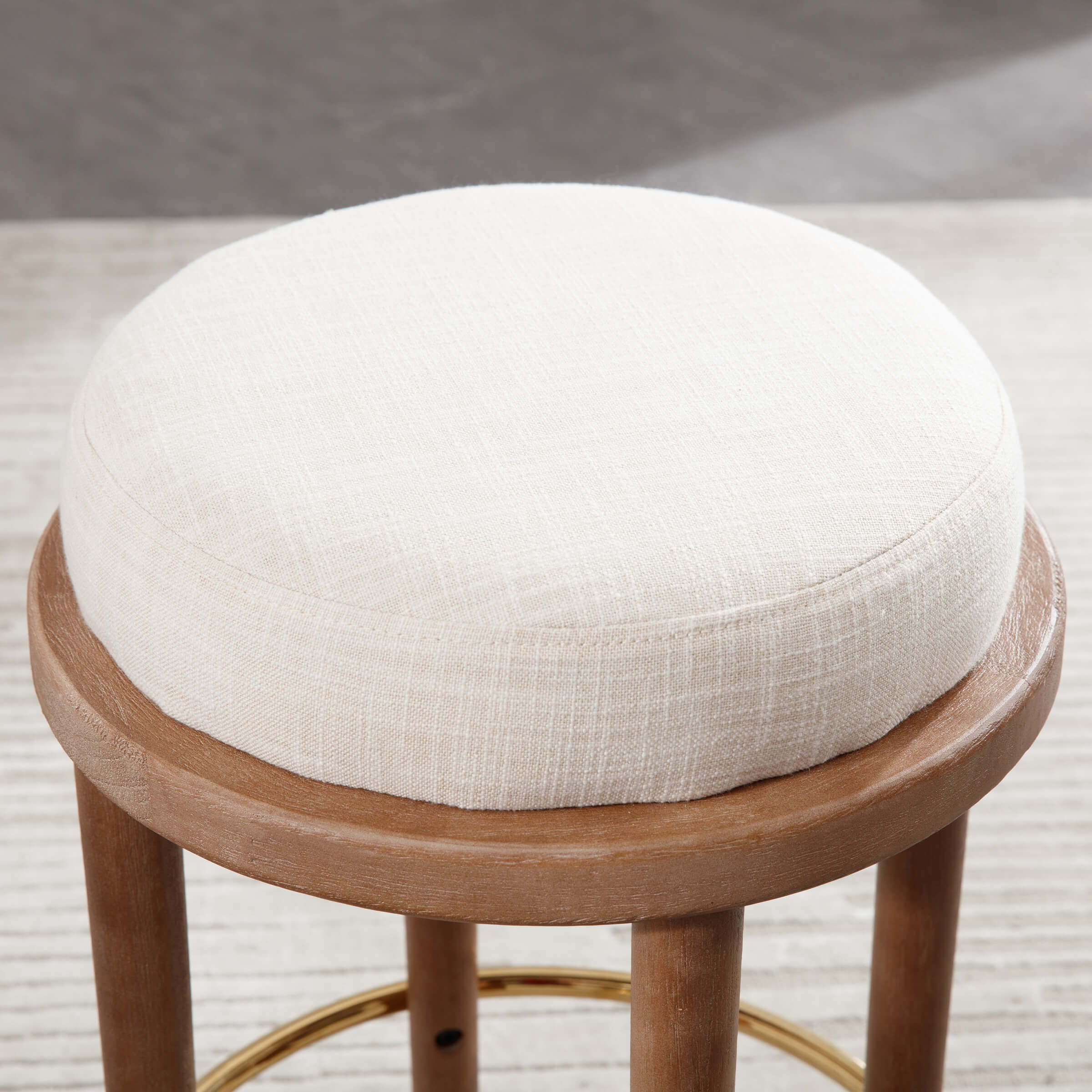 Close-up of round beige upholstered stool seat with wooden base