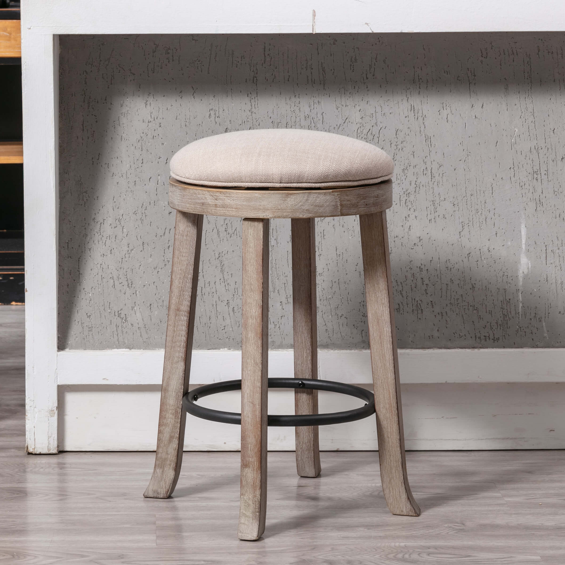 Two upholstered round backless swivel counter stools with beige cushions and wooden legs