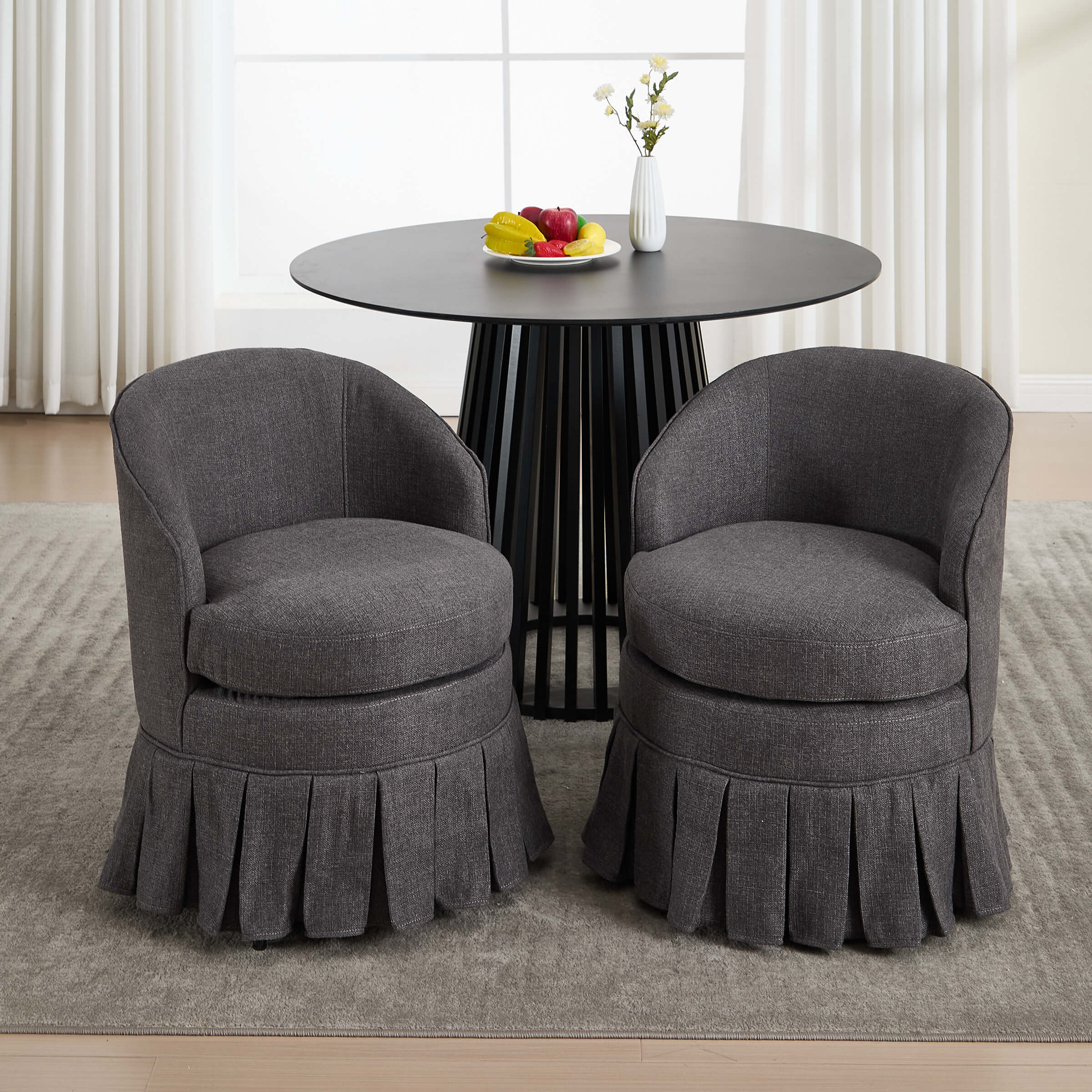 Two dark chairs with pleated skirts around round table