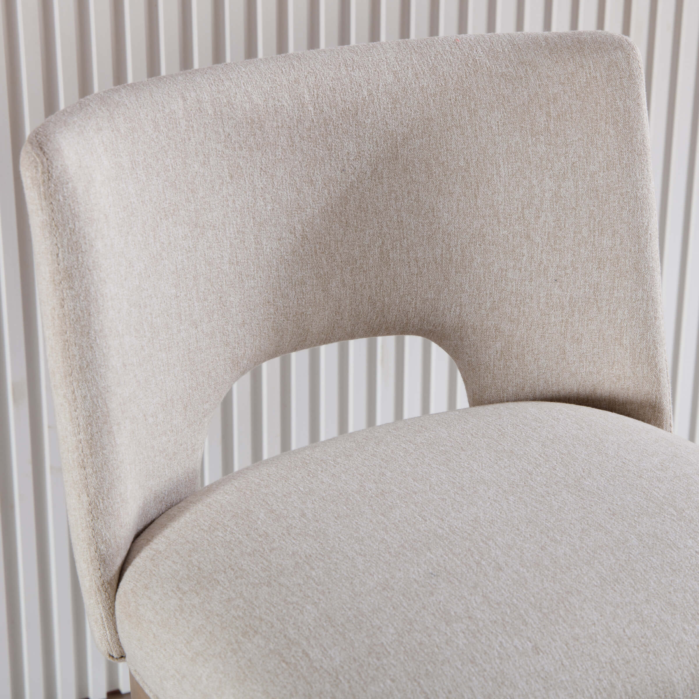 Close-up of beige upholstered chair back and seam