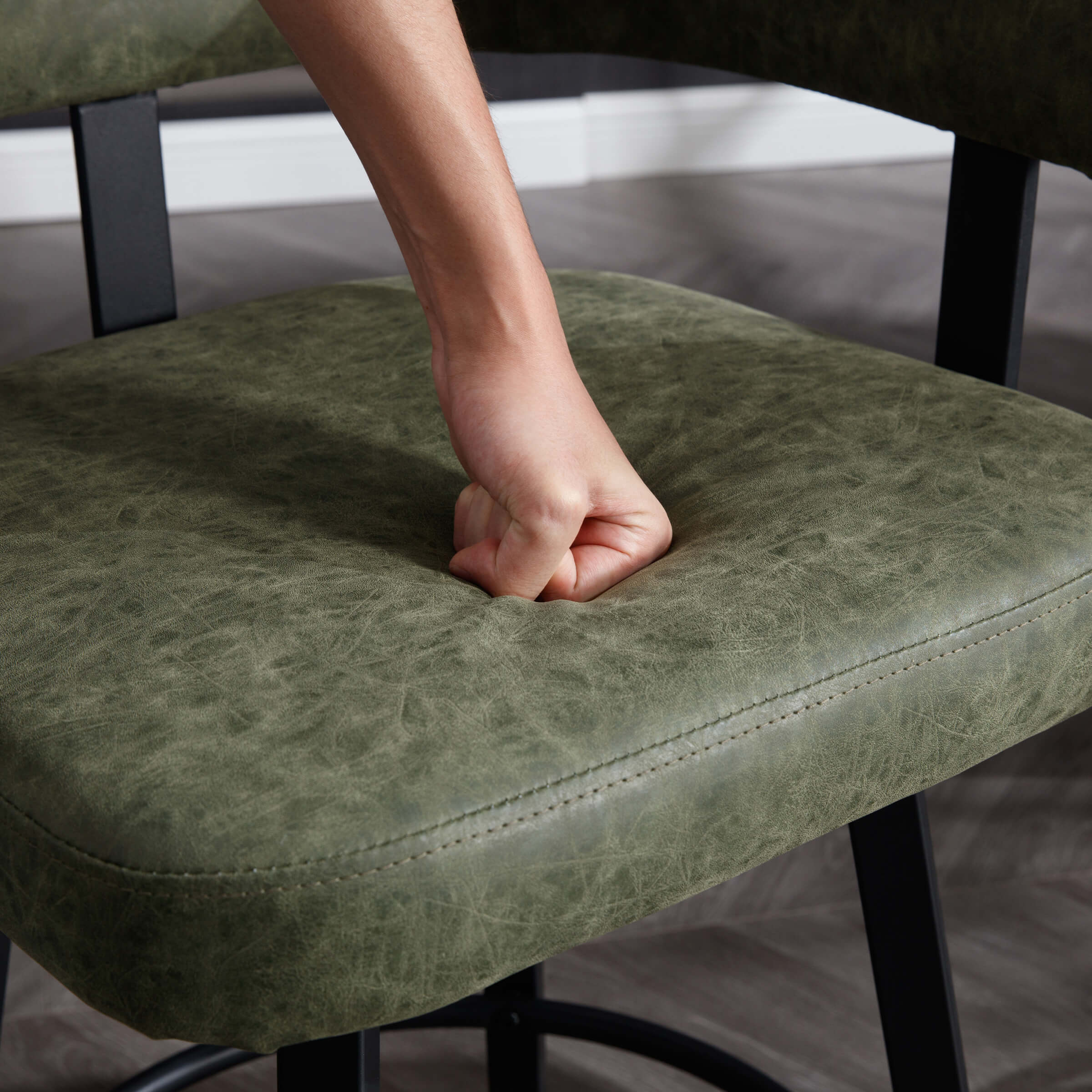 Hand pressing into cushioned seat of bar stool