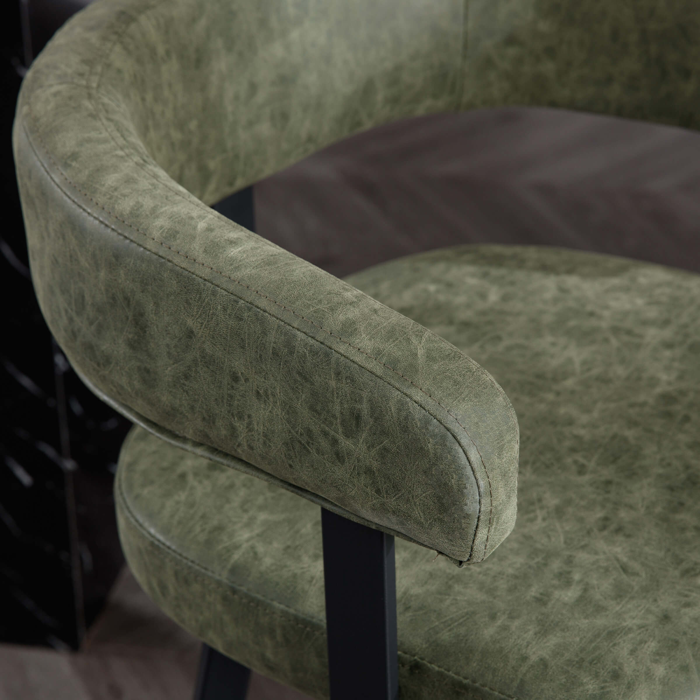 Close-up of green leather armrest on bar stool