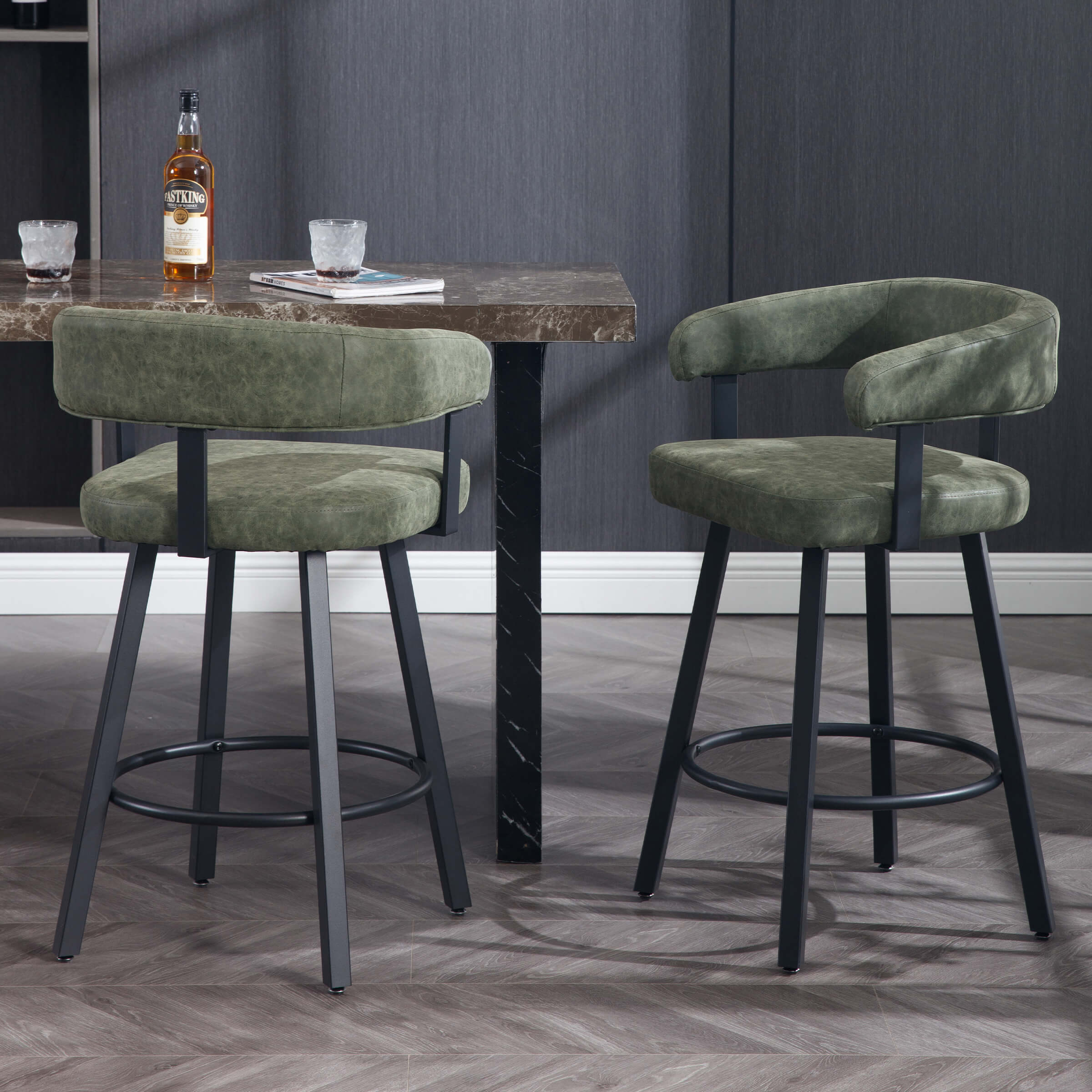 Two green upholstered bar stools at a marble-top table in a dark modern kitchen