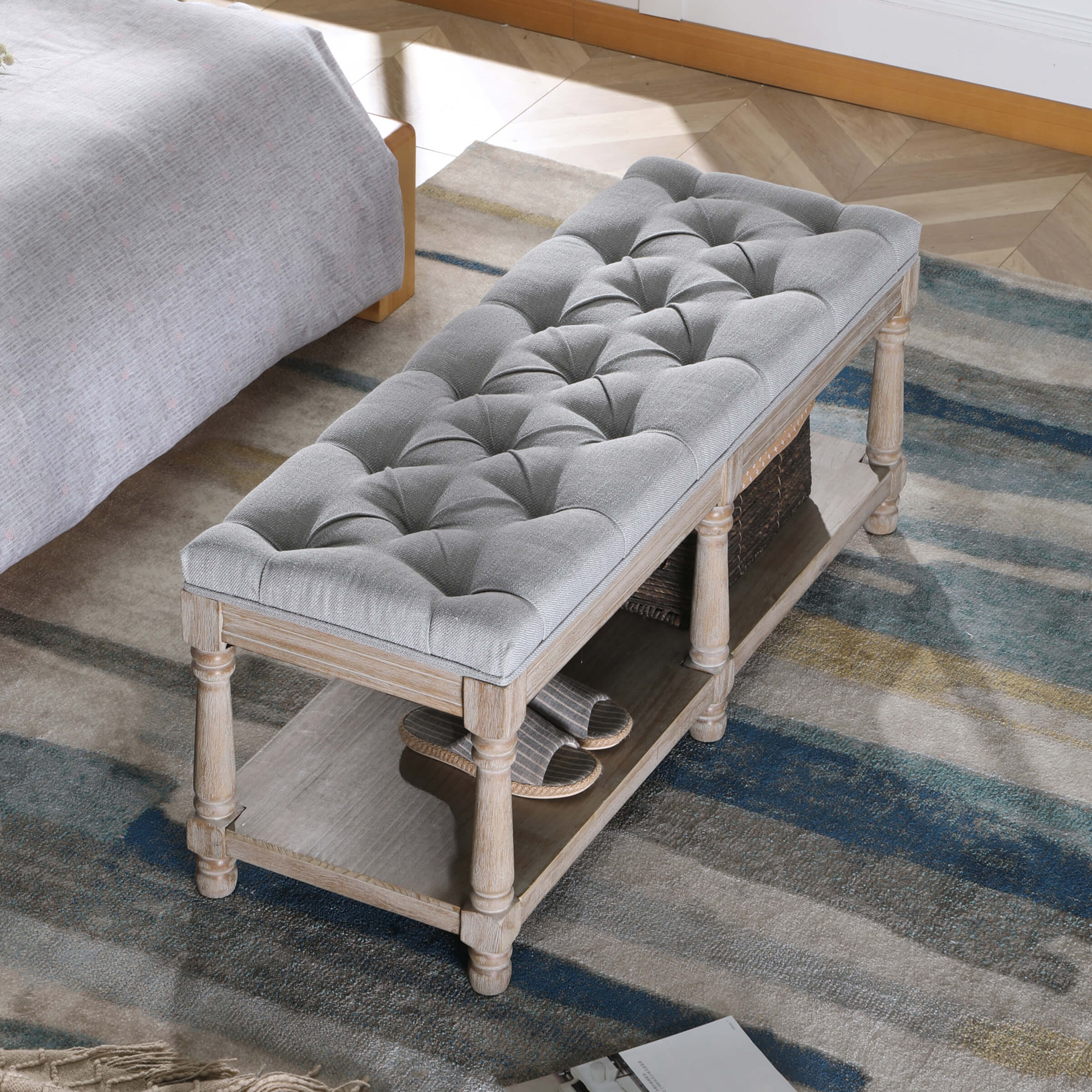 Tufted grey upholstered bench in a bedroom setting