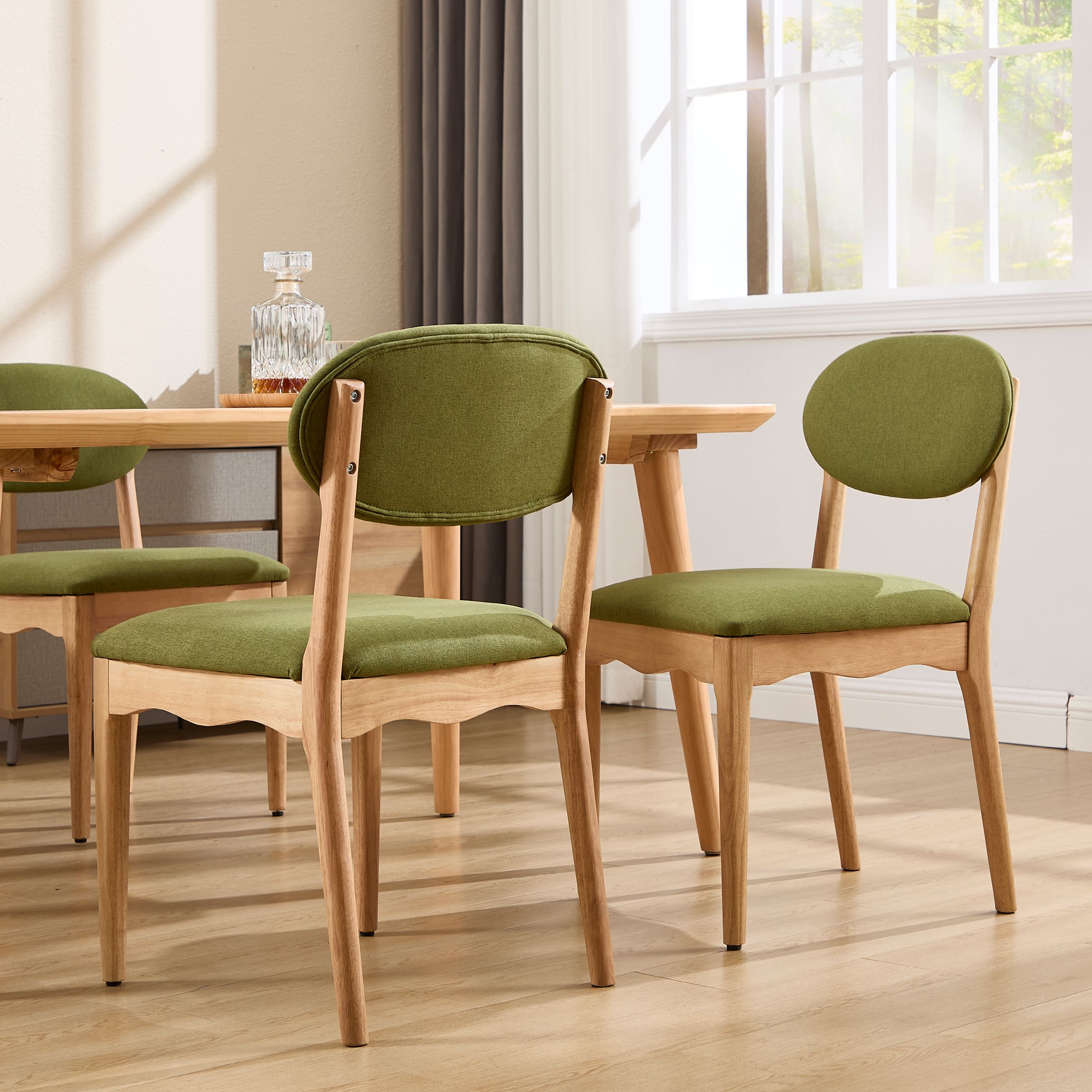 Set of two green upholstered dining chairs from a front-side angle