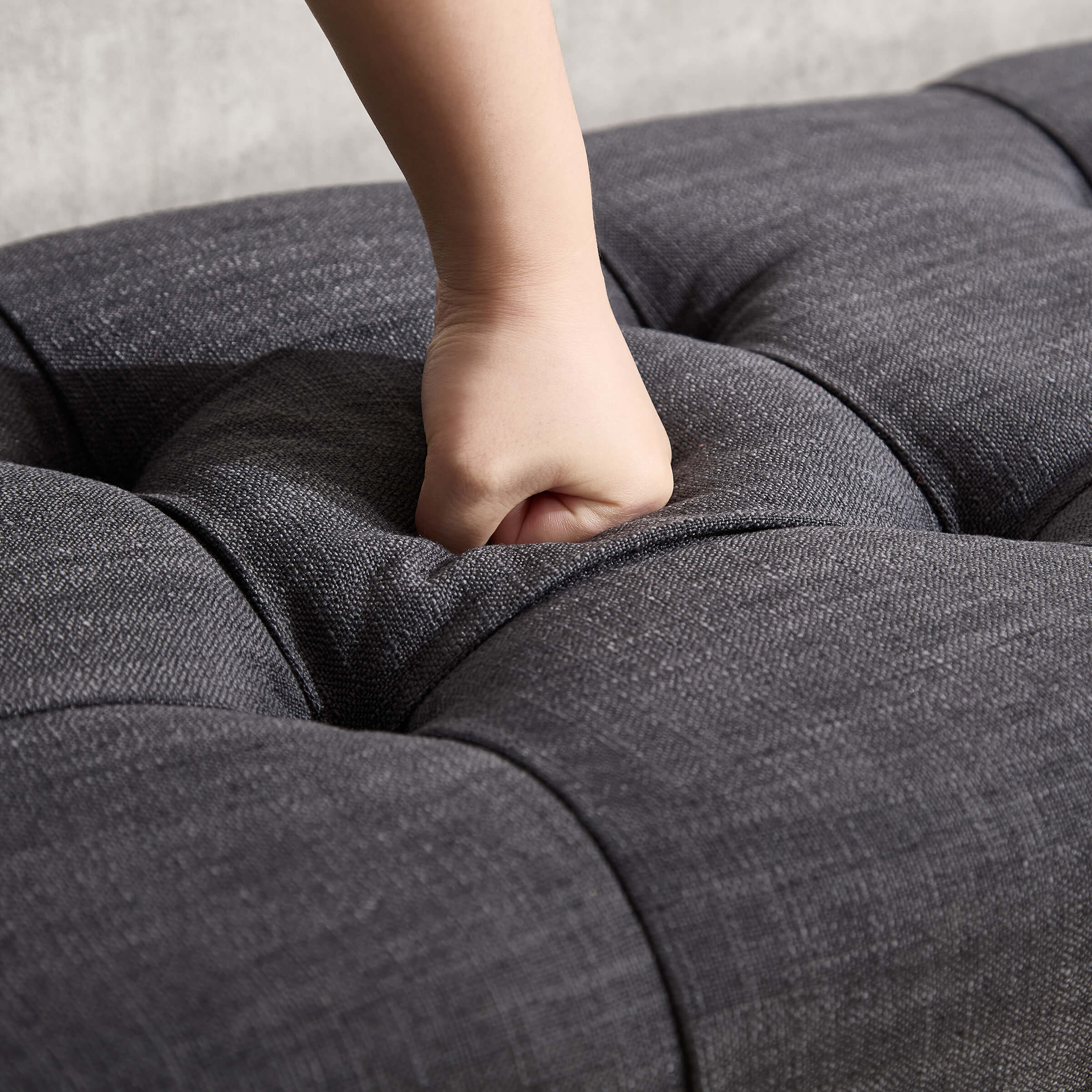 Finger pressing tuft on cushion illustrating softness