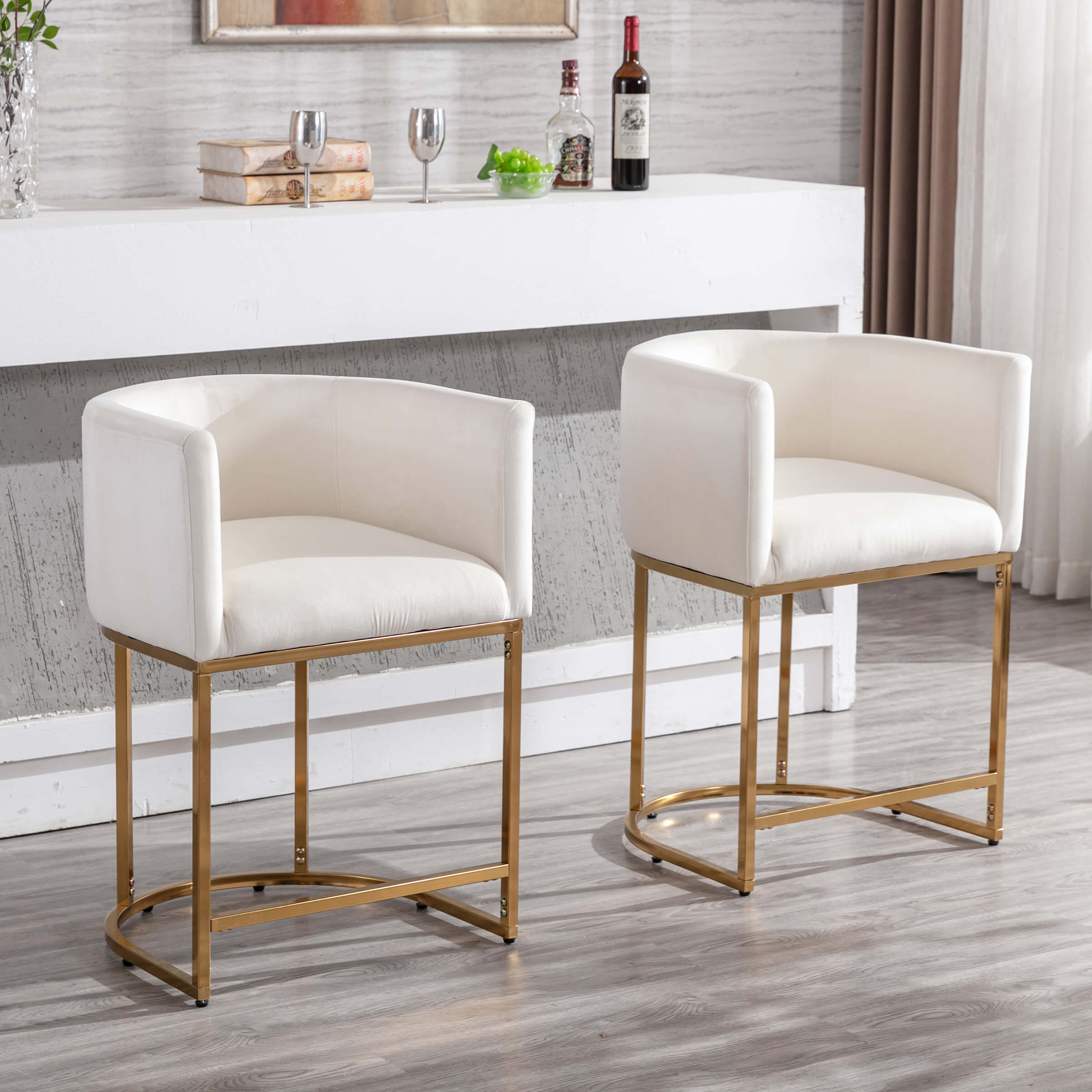 Two white upholstered counter stools with gold frames placed in a kitchen/bar setting