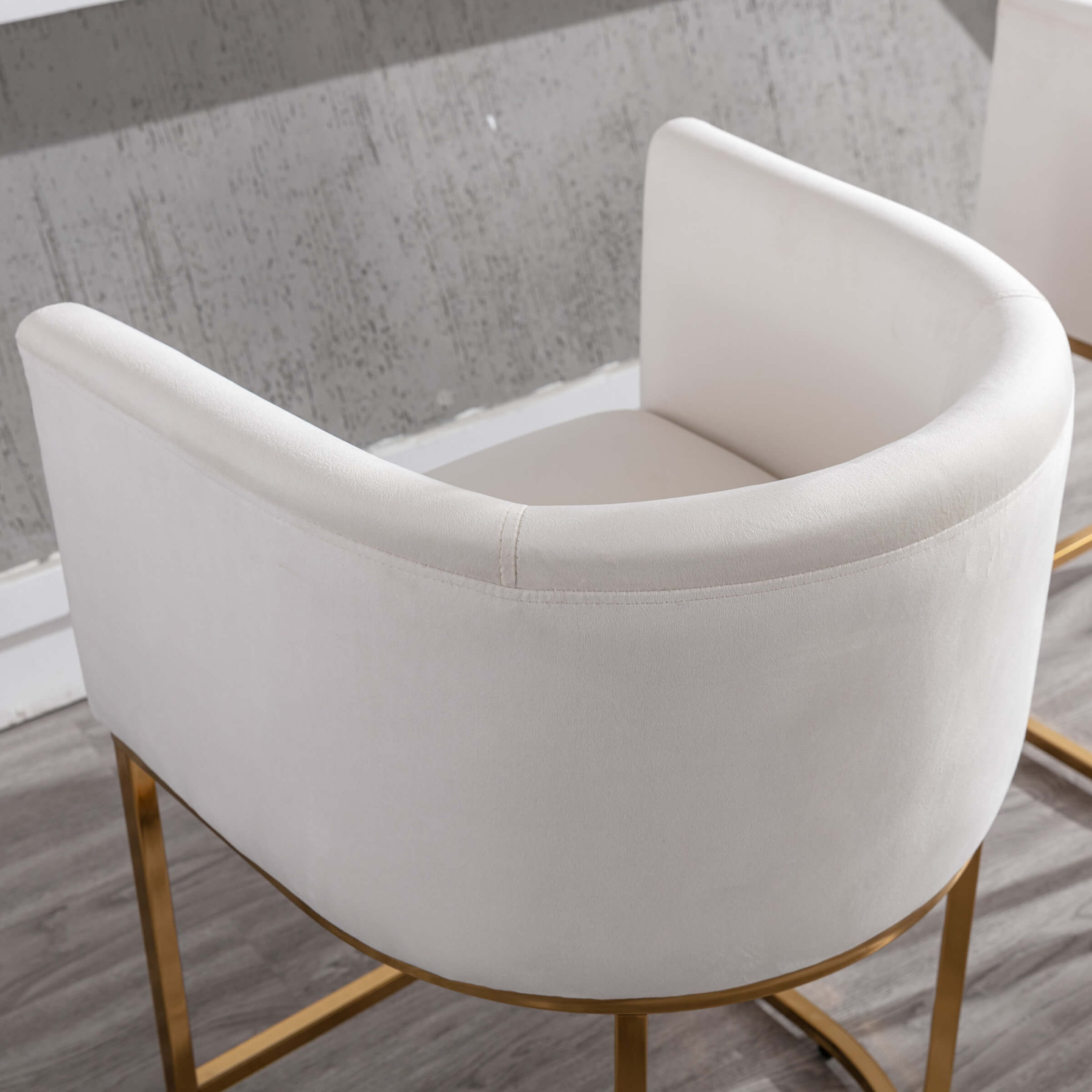 Angle view of white upholstered chair with gold base