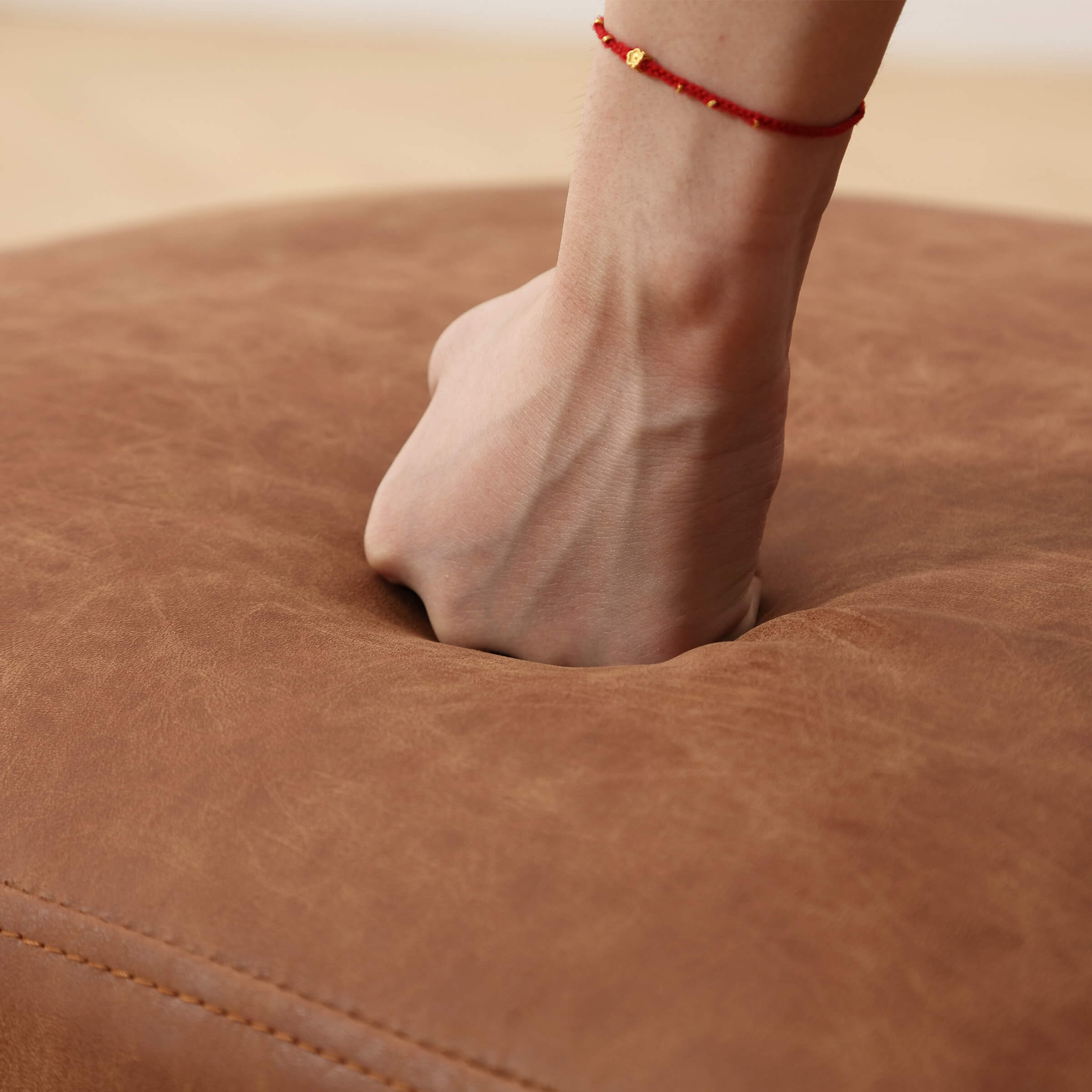 Hand pressing into brown leather-like cushioning