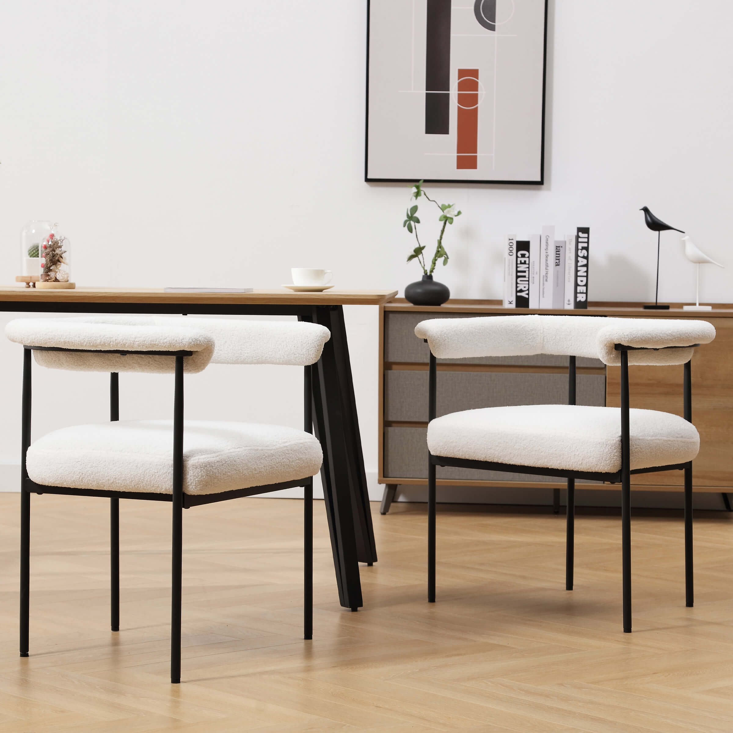 Two white upholstered dining chairs with black metal frame around a wooden table