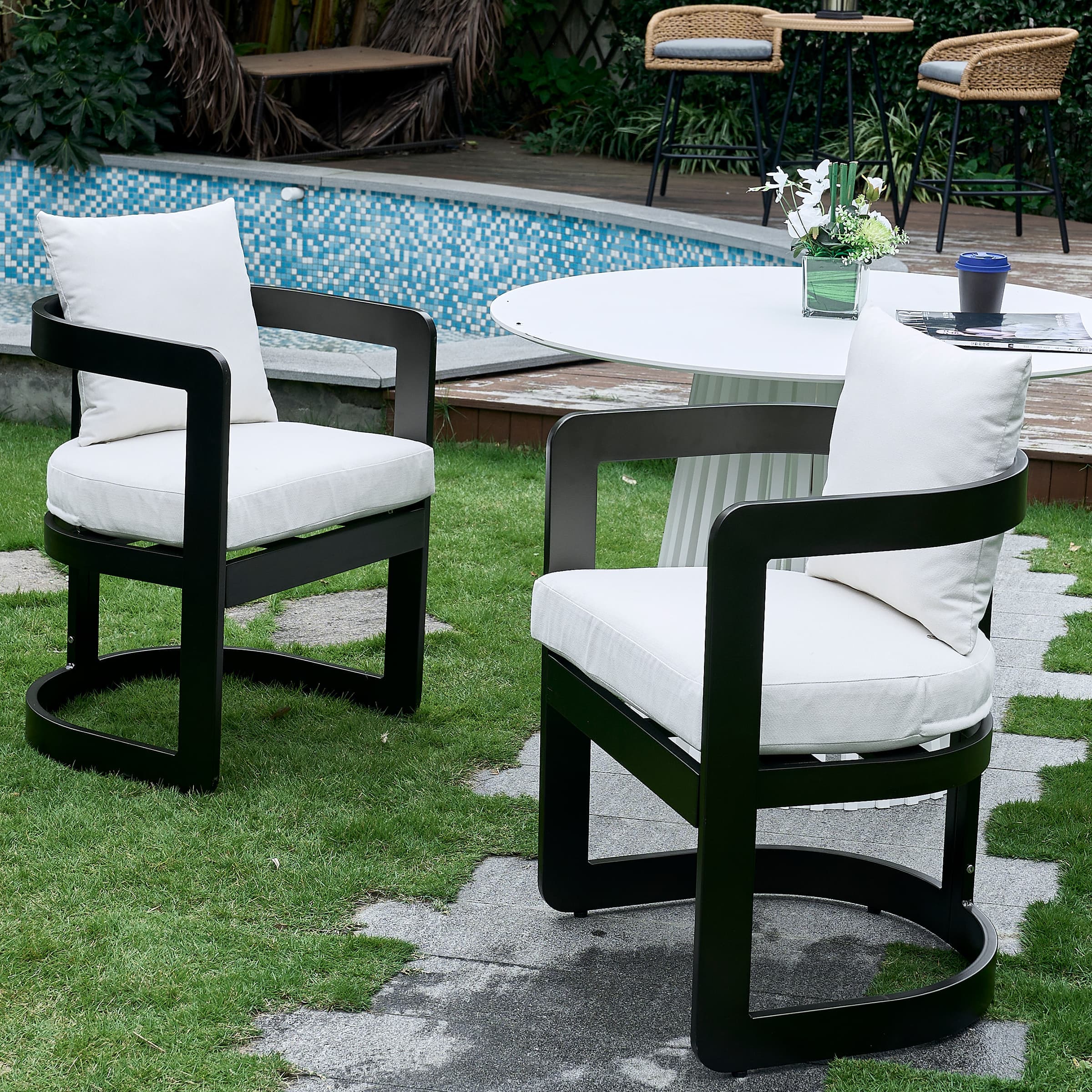 Outdoor chairs with white cushions around a white round table by pool