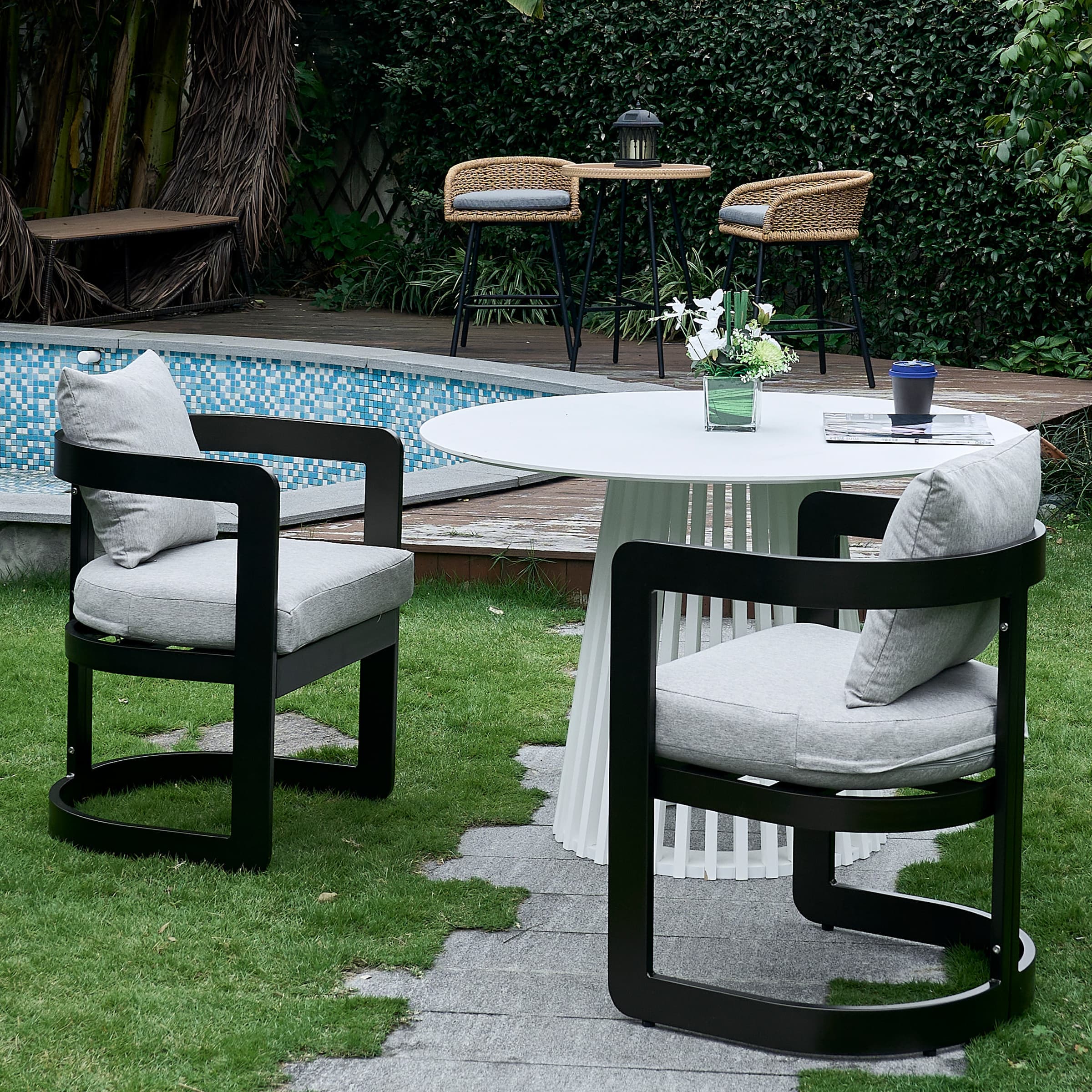 Set of two chairs around round white table on lawn