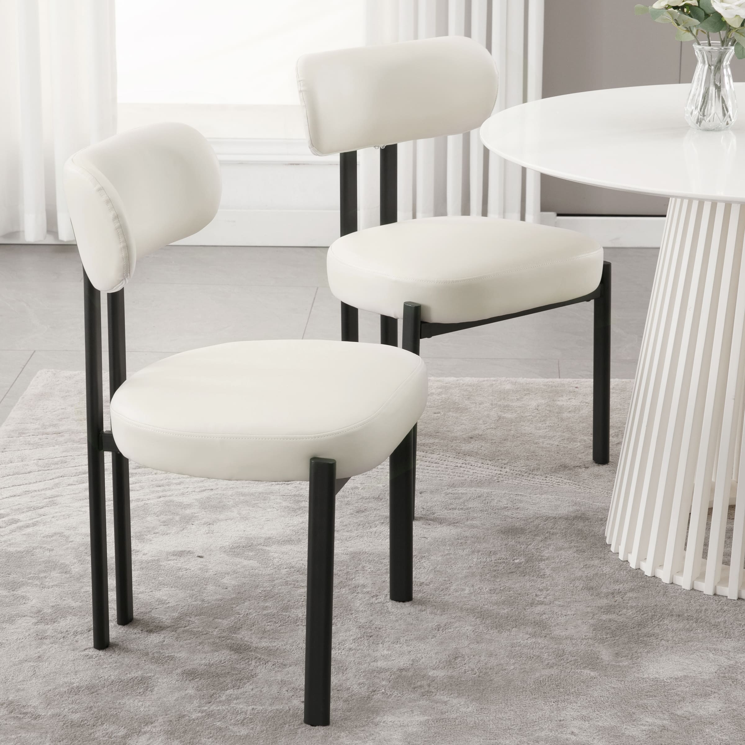 Two white chairs around a white round table