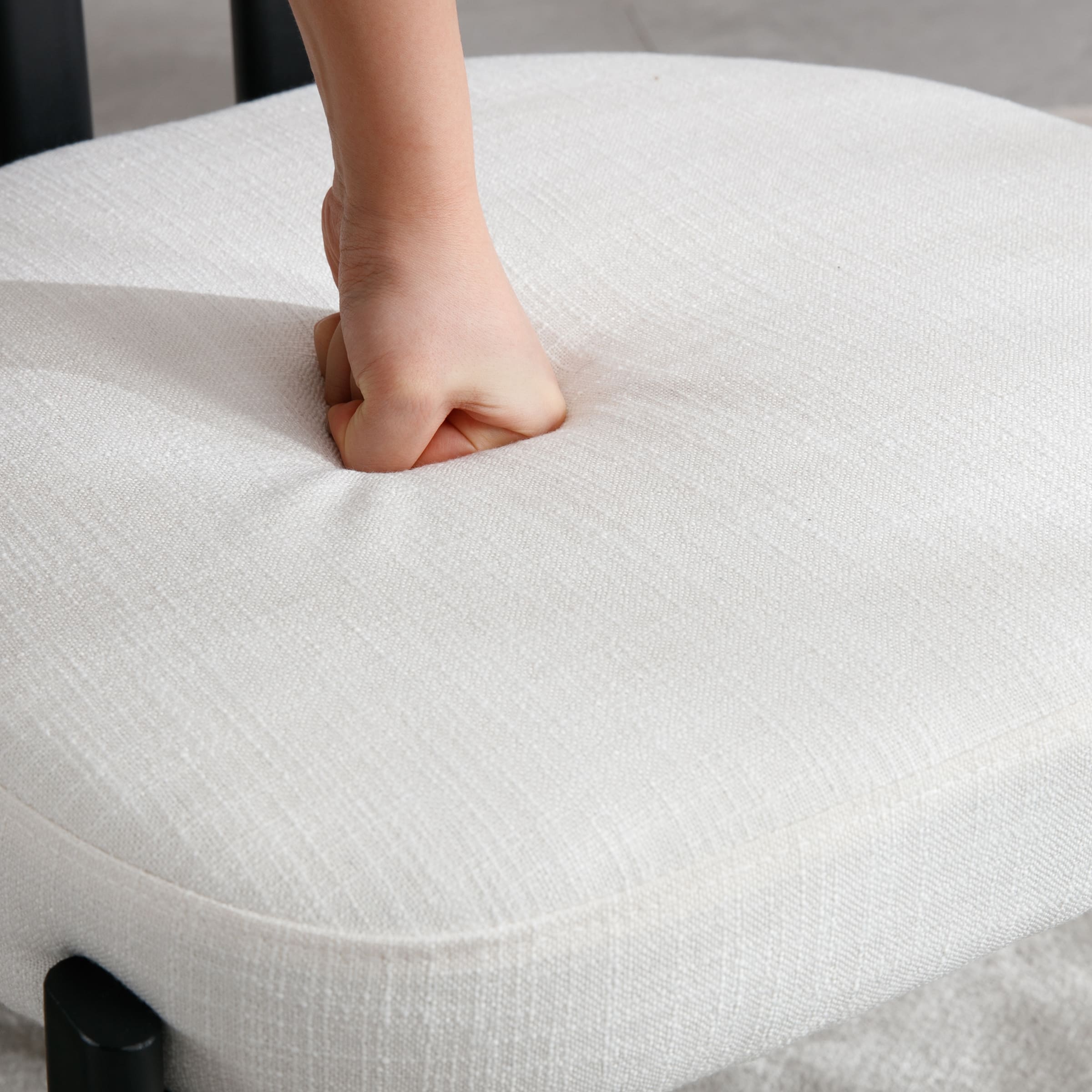 Close-up of chair seat cushion being pressed by a hand