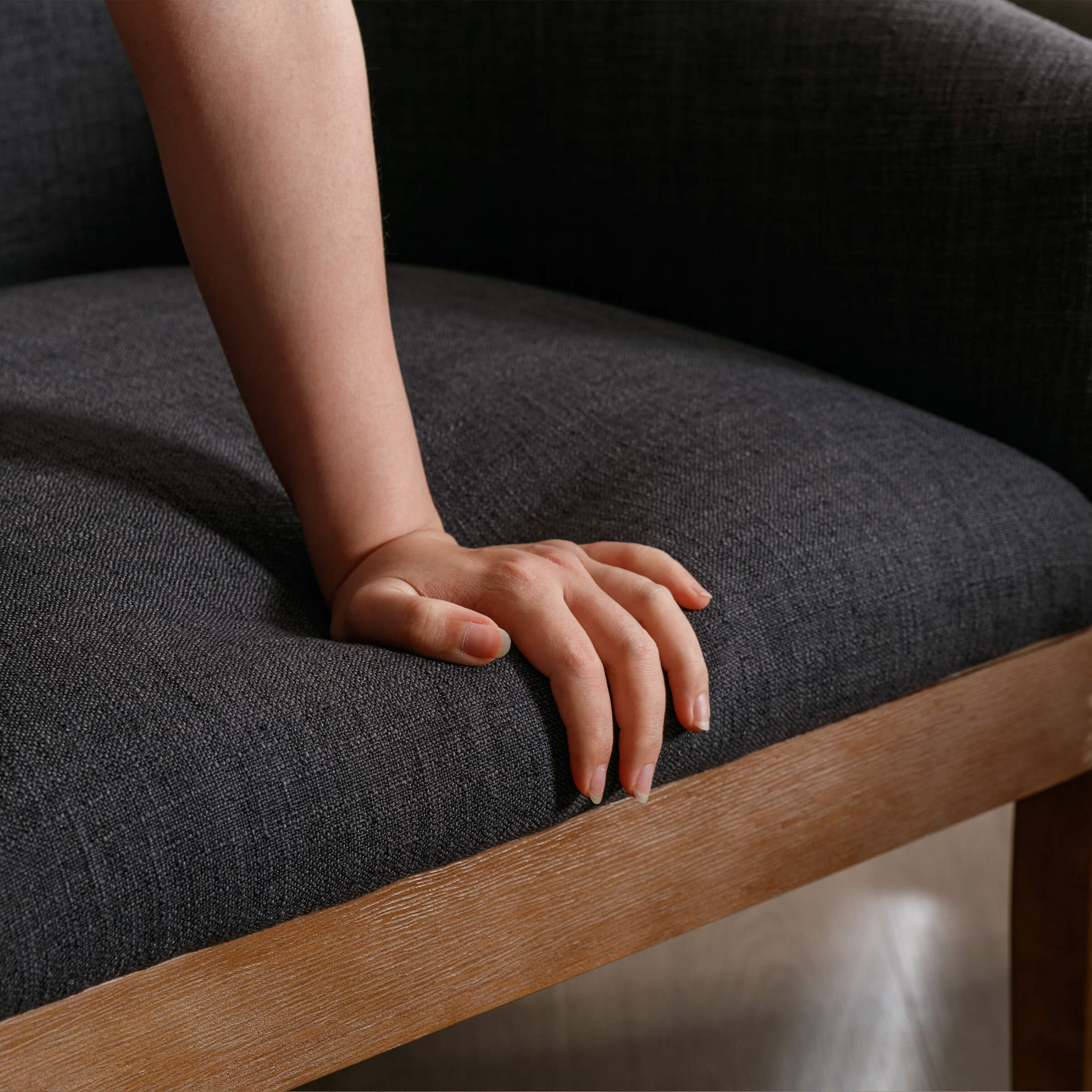 Person’s hand on dark chair seat