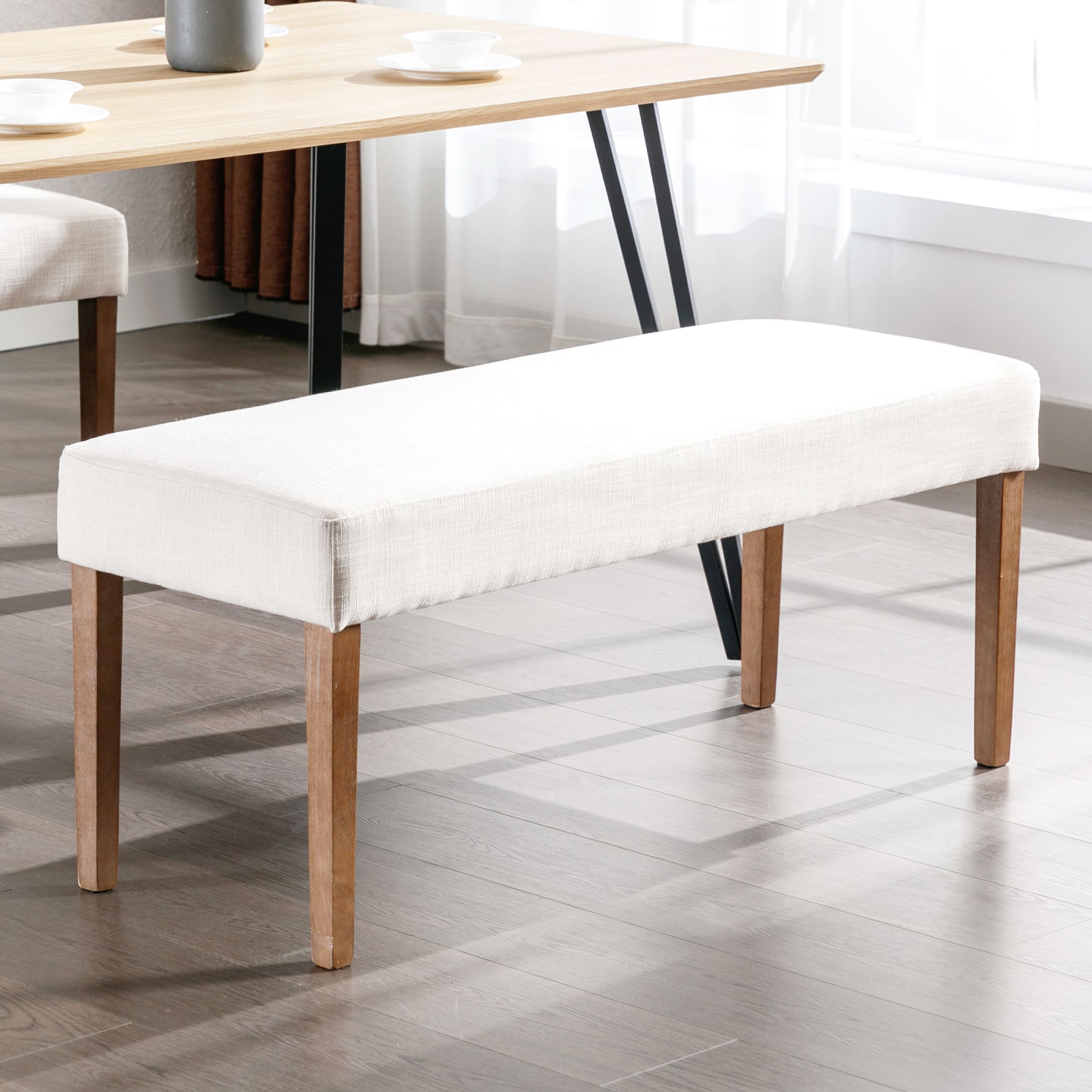 Beige upholstered bench from side under dining table