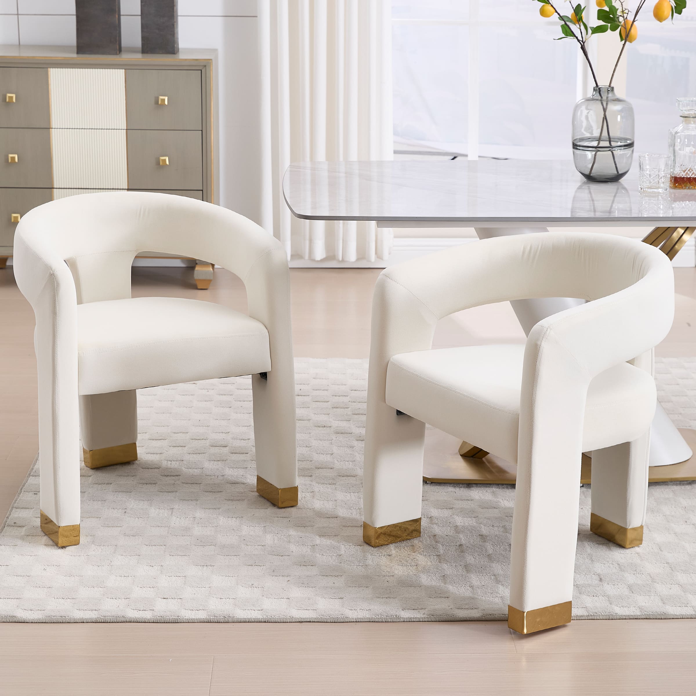 Set of two open-back velvet dining chairs in white around a dining table