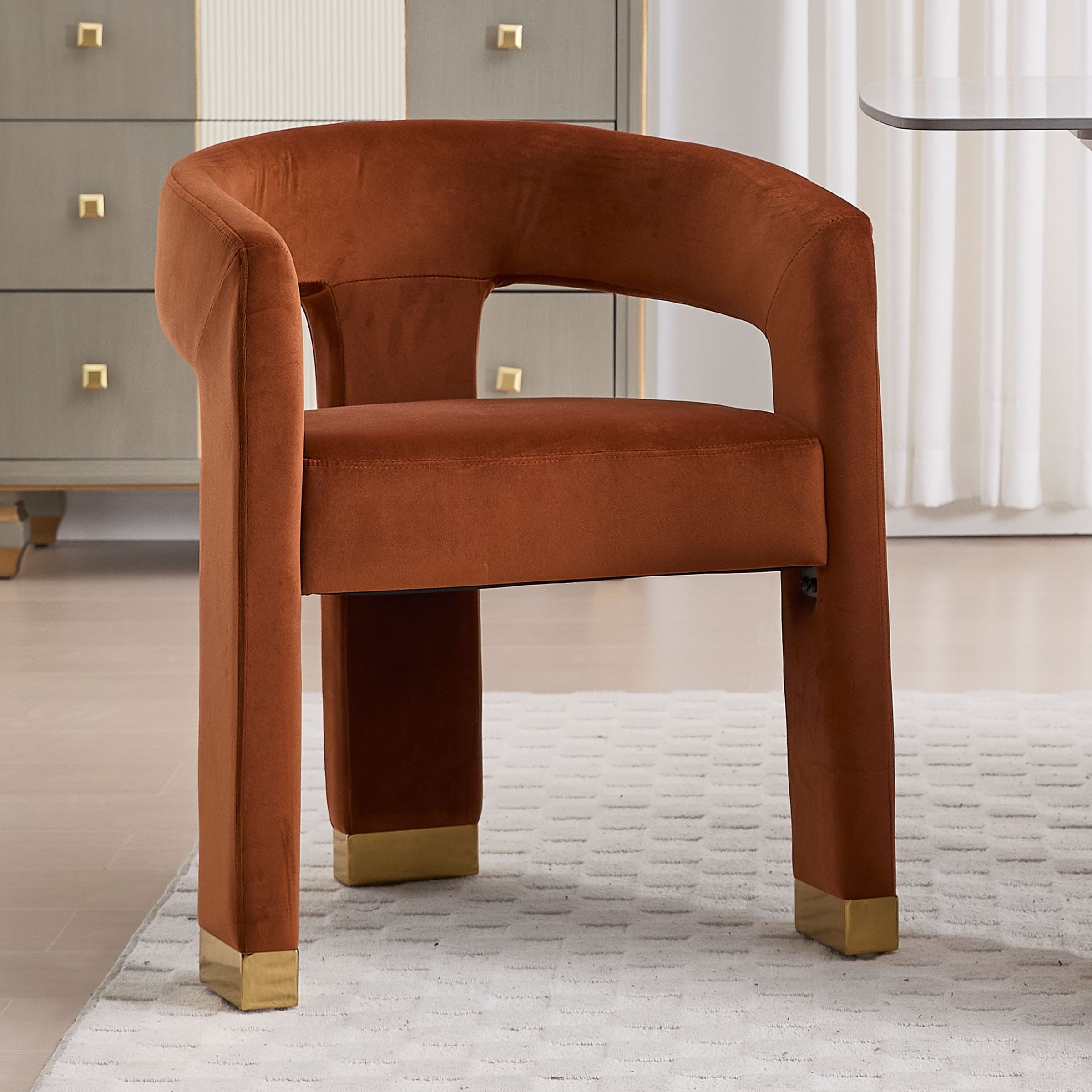 Orange-brown velvet chair with gold feet around table