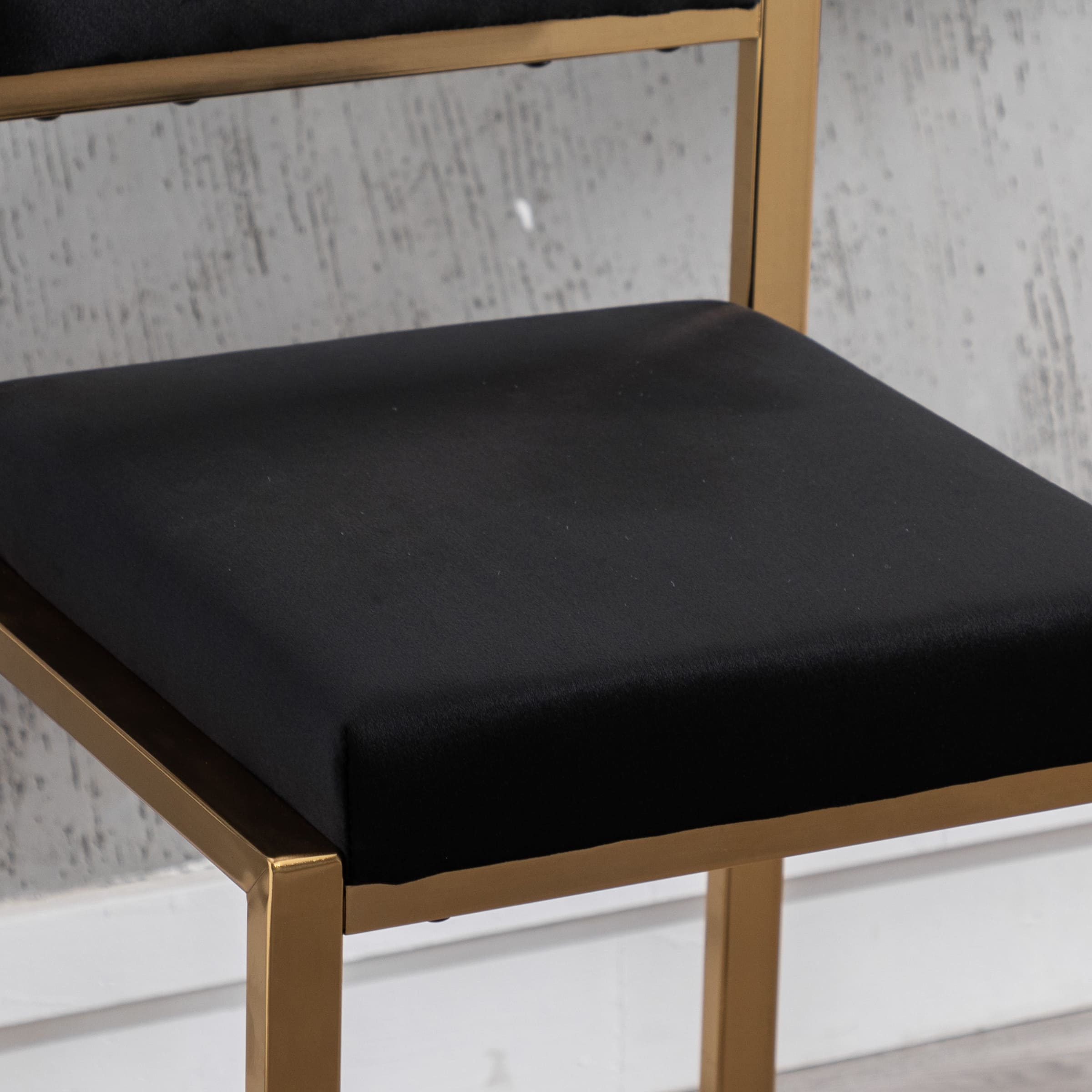 Close-up of black seat cushion on gold frame stool