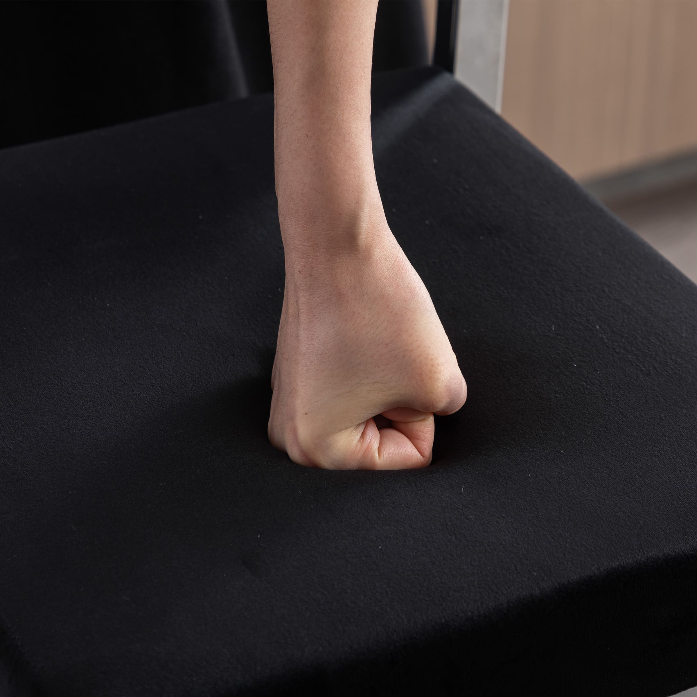 Hand pressing into black seat cushion