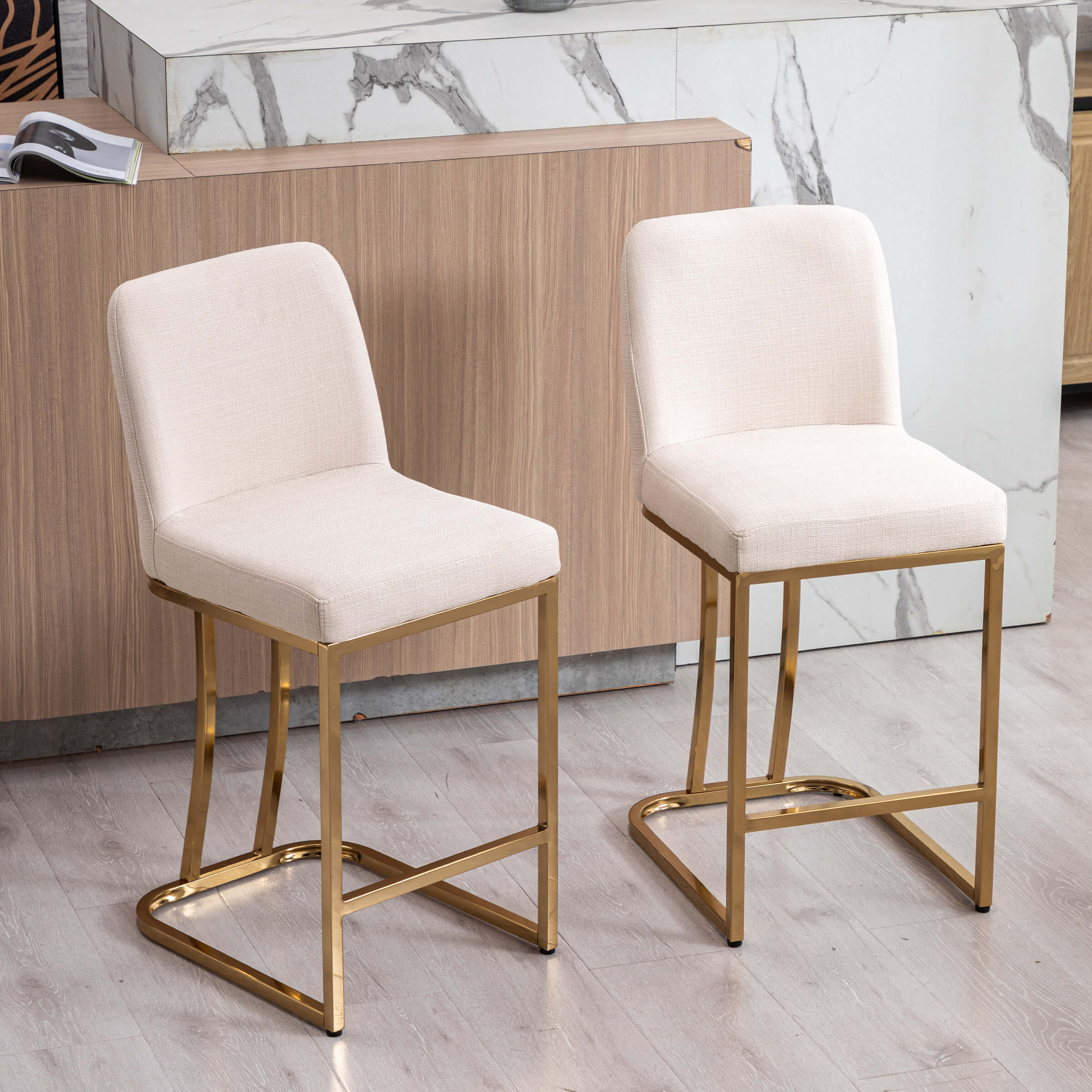 Two beige upholstered stools at a white marble bar