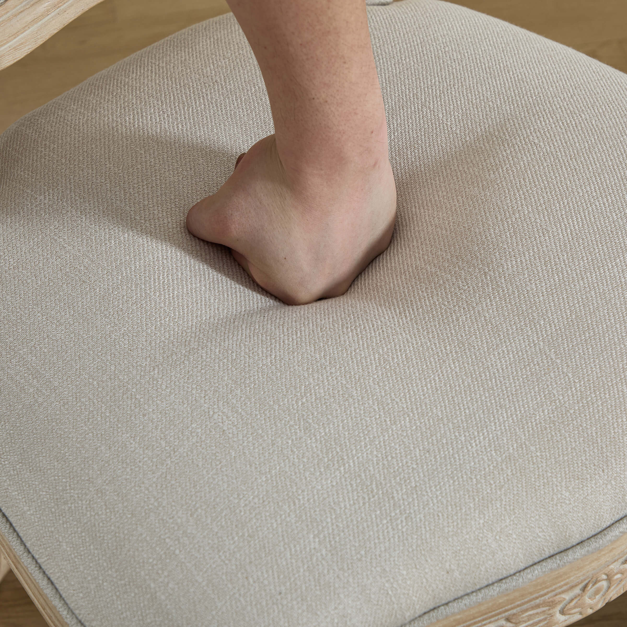 Foot of chair with hand pressing upholstery